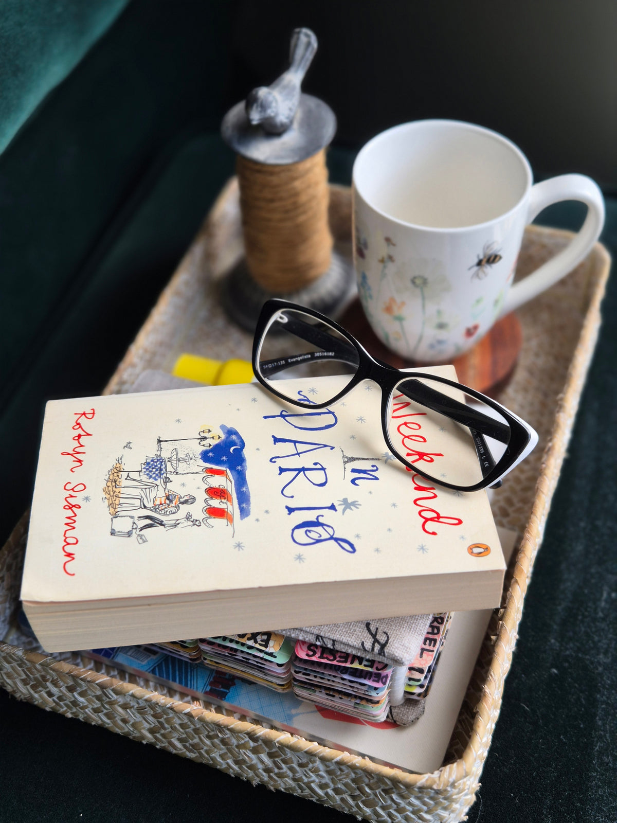 Styled vignette from The Curated Life Journal Issue 1 — A Weekend in Paris book, reading glasses, bee mug and twine spool on a woven tray