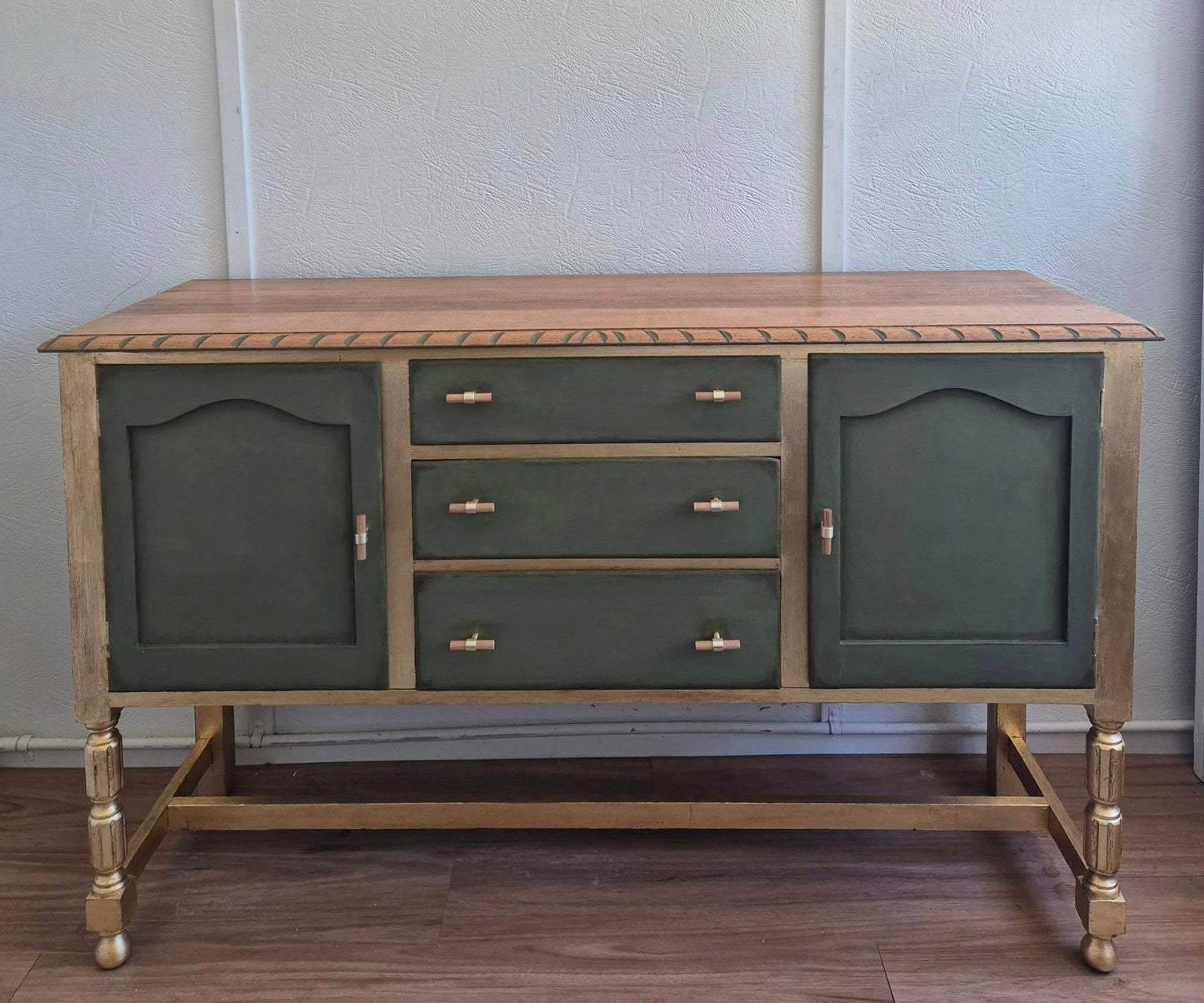 An elegant olive green and gold sideboard buffet table with drawers and gold leaf accents.