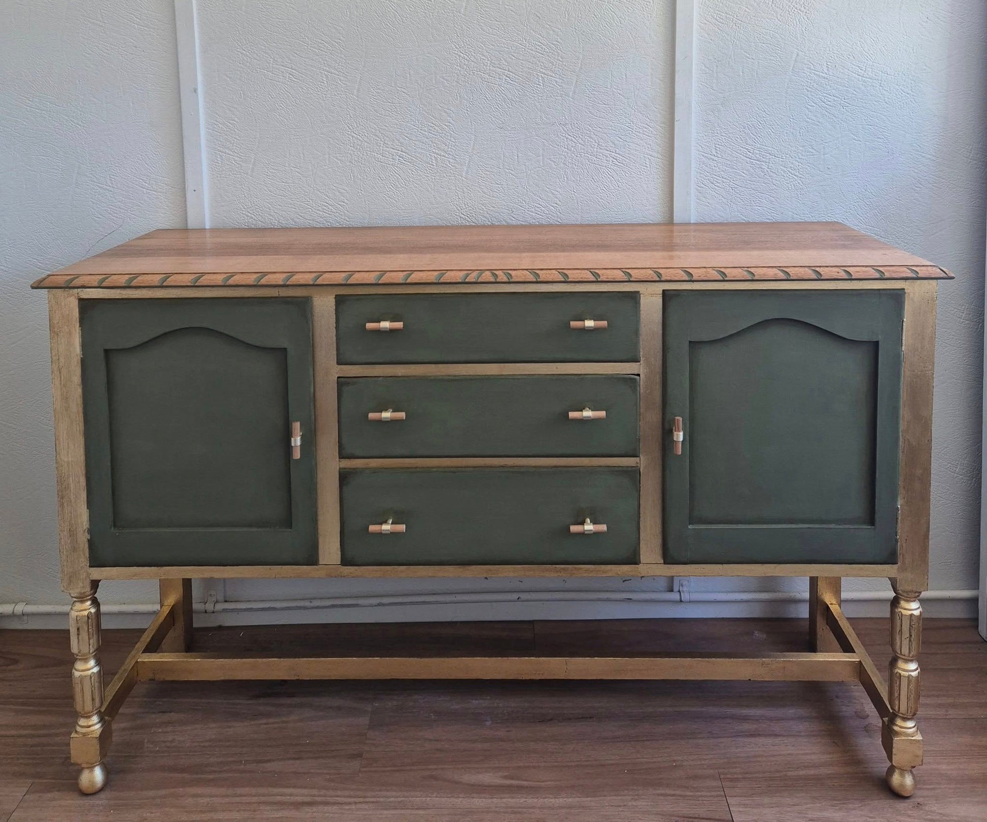 An elegant olive green and gold sideboard buffet table with drawers and gold leaf accents.
