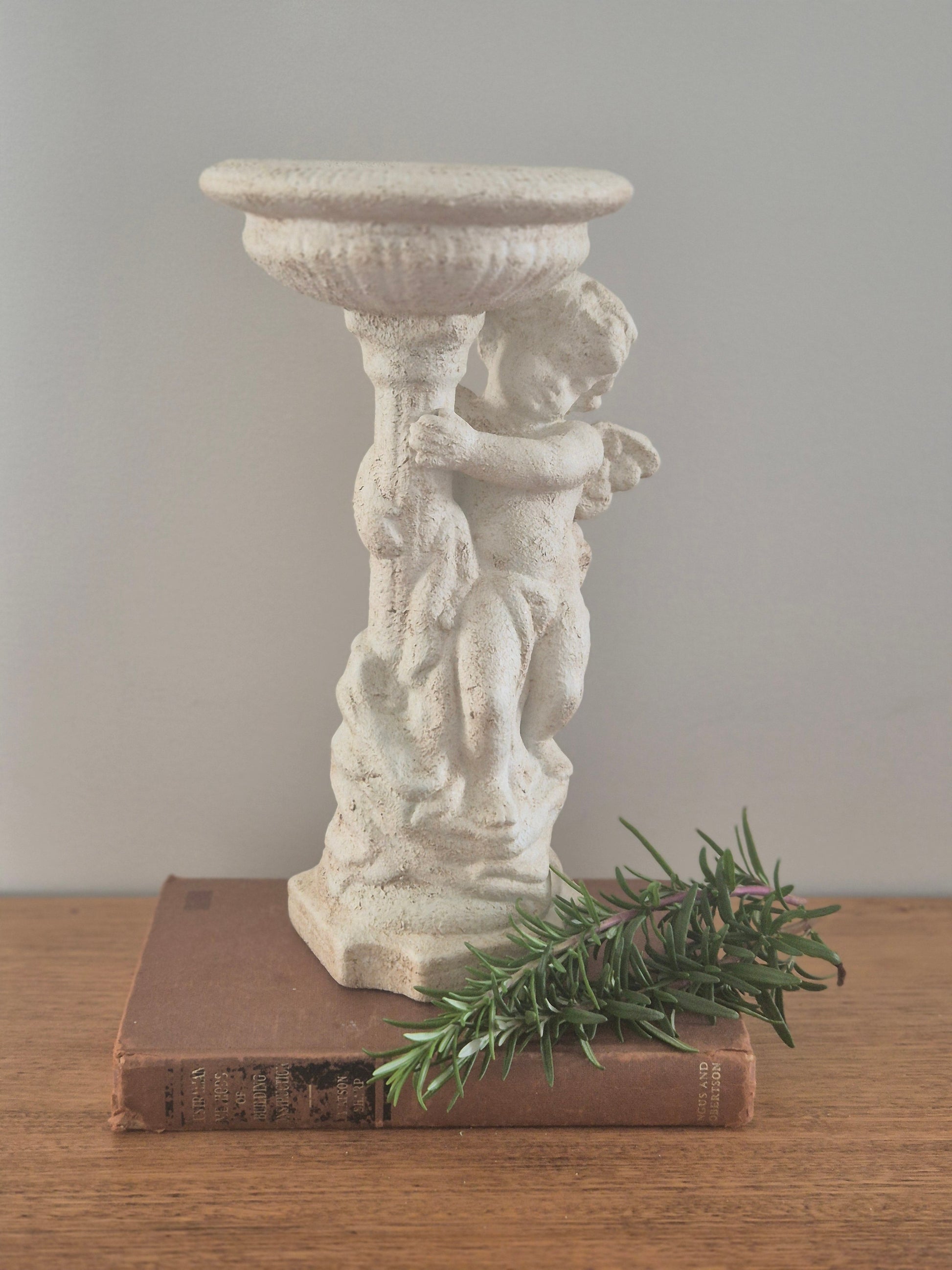 Cherub pedestal birdbath stone finish styled with vintage book and rosemary