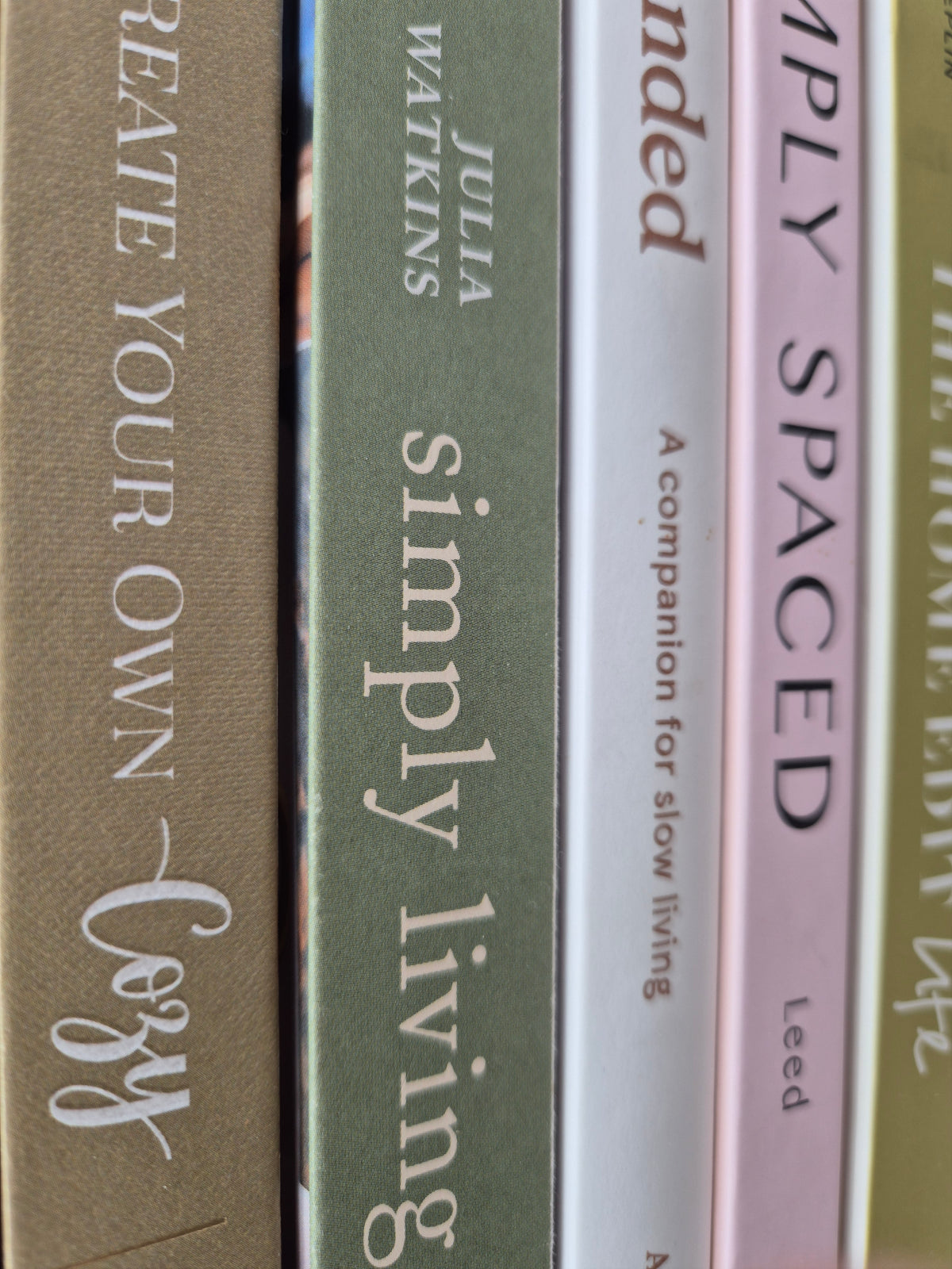 Styled detail from The Curated Life Journal Issue 2 — curated book spines in sage, blush and grey including Simply Living and a companion for slow living
